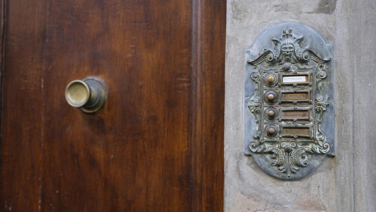 Puerta de madera de un edificio antiguo con portero eléctrico de bronce